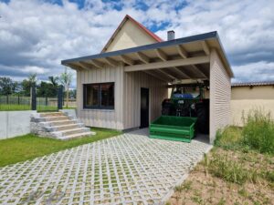Holzbau-Carport mit landwirtschaftlicher Maschine darunter