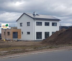 Neubau eines Einfamilienhauses mit weißer Putzfassade und Baustelle im Vordergrund
